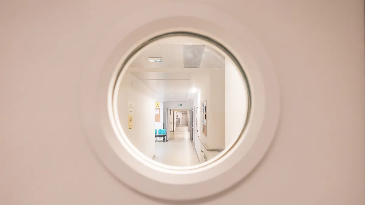 Couloir d’hôpital vu à travers un hublot de porte