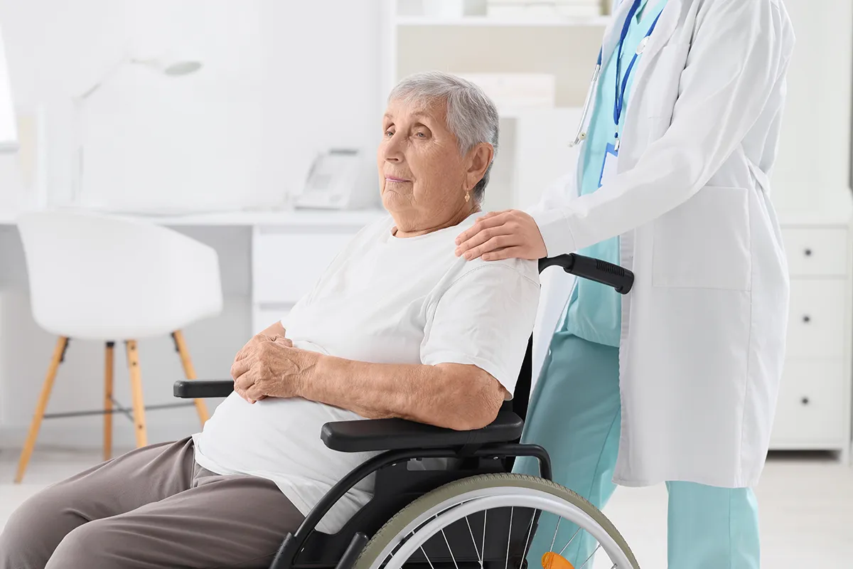 Femme en fauteuil roulant, guidée par un soignant du Centre Hospitalier de Carcassonne