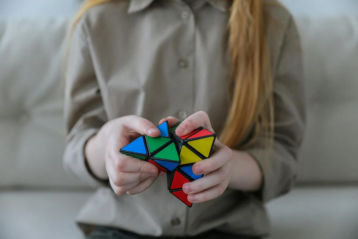 Enfant manipulant un casse-tête coloré pour travailler la coordination et la réflexion cognitive.