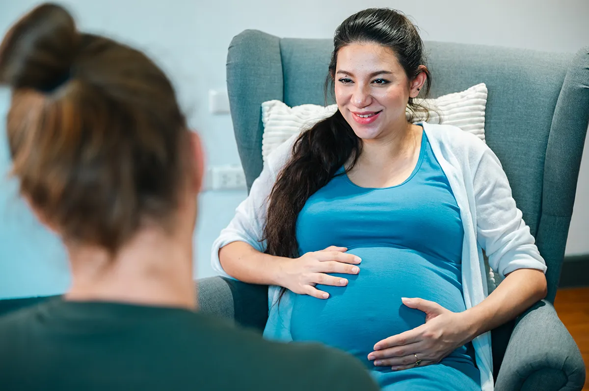 Femme enceinte en entretien avec un professionnel pour un accompagnement de grossesse et parentalité.