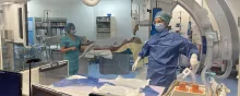 Équipe soignante en salle d’intervention avec patient installé sur la table.