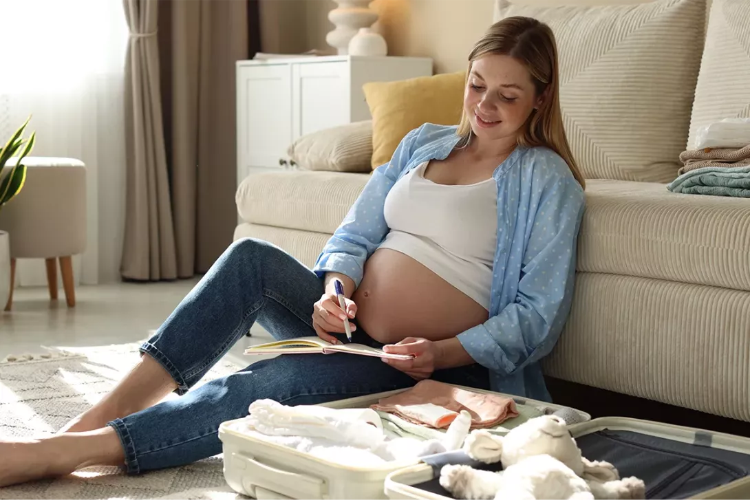 Femme enceinte préparant la valise de maternité avant l’accouchement à domicile.
